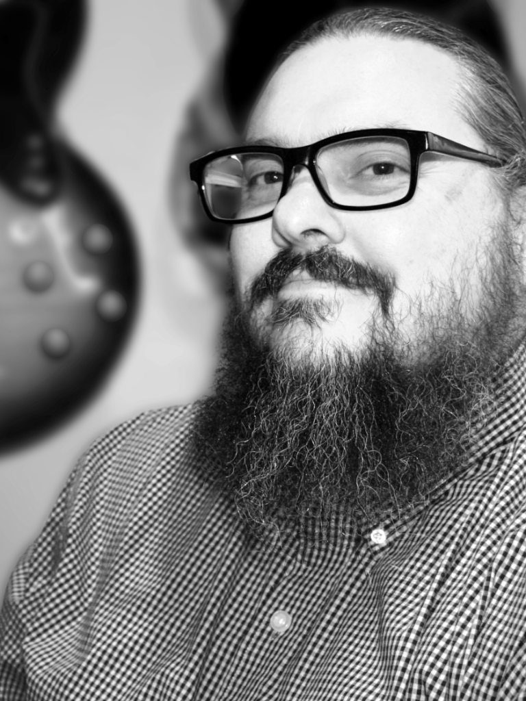 Nick Croft. Large man with a dark bears and long hair pulled back into a ponytail.